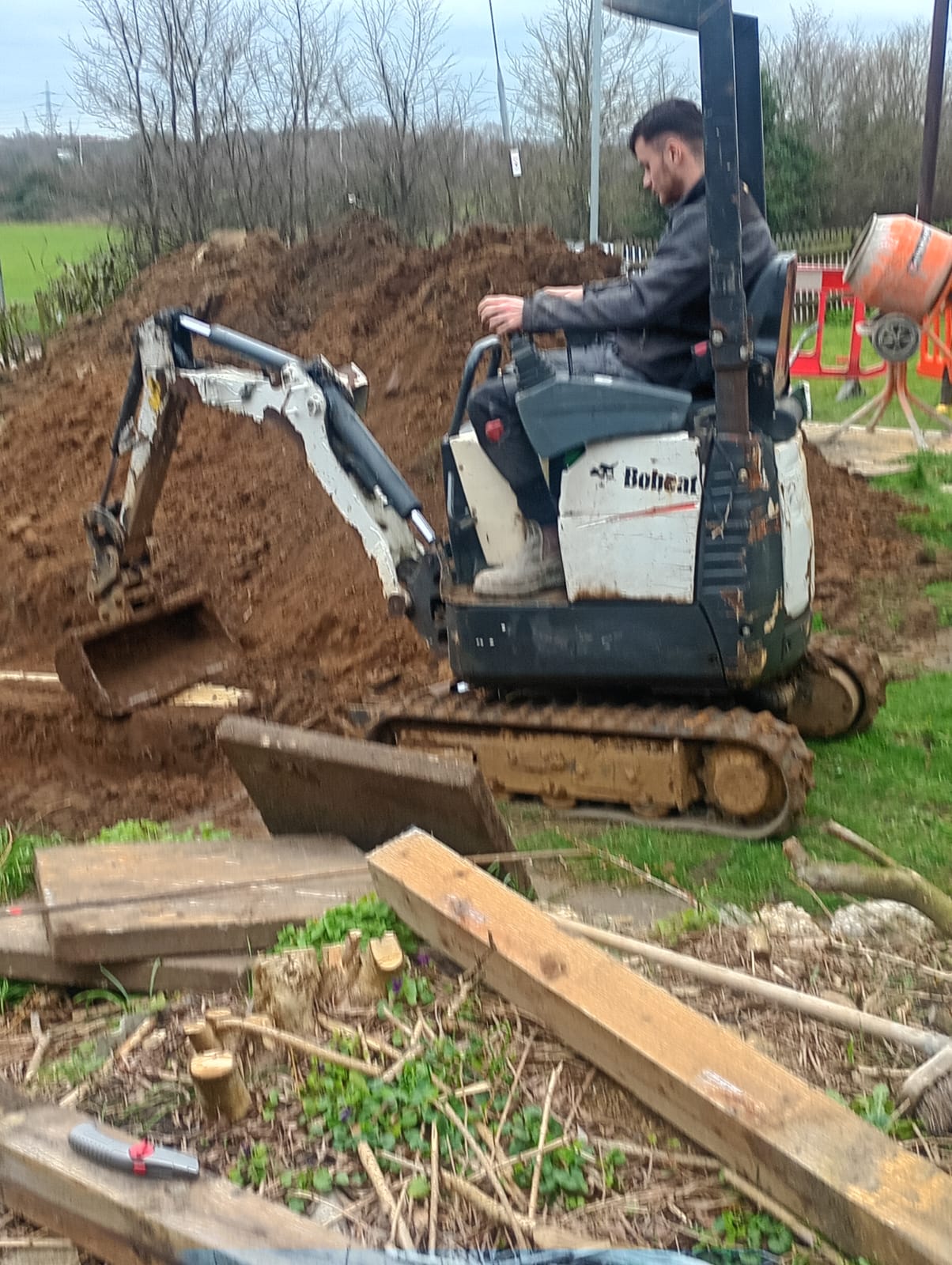 Operator using a Bobcat mini excavator on a rural residential site